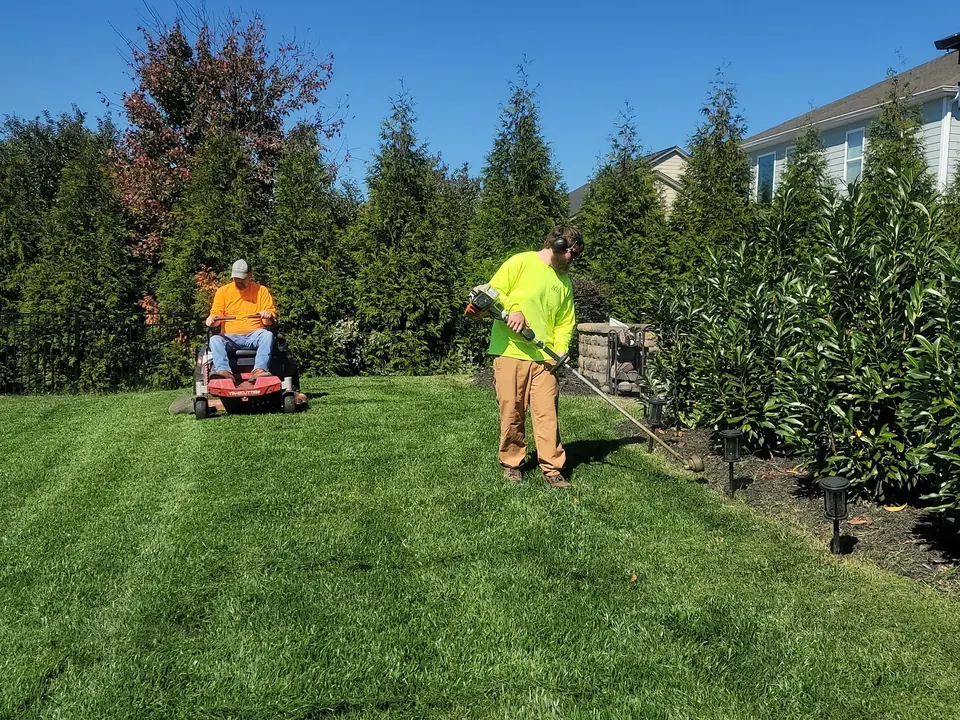 A landscaper mowing a residential lawn